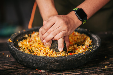 Preparation of Indonesian Balinese traditional spicy sauce sambal matah in mortar with pestle,...