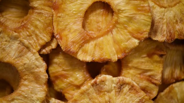 Slices of dried pineapple on rotating background. Top view. Vegan, vegetarian diet. Healthy lifestyle. Dried fruits background. Sweet pineapples, organic food.