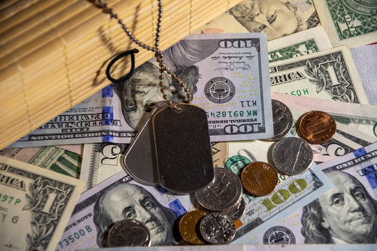 American dollars and coins are scattered on the flag, and army medallions lie near a wooden piggy Bank. Concept: pension for the military, army memories, the price of war, state support for military p