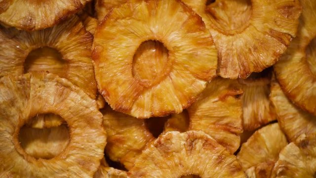 Slices of dried pineapple on rotating background. Top view. Vegan, vegetarian diet. Healthy lifestyle. Dried fruits background. Sweet pineapples, organic food.