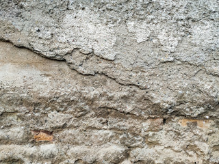 Old and damaged cement and concrete wall or floor ground with different layers showing, in need of repair, made of stone and other materials