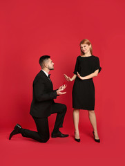 Young woman rejecting engagement ring from boyfriend on red background