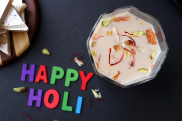 Indian Holi festival food or drink Thandai. It is an Indian cold drink prepared with a mixture of Milk, Dry fruits, sugar & spices. Garnished with Almonds, Pistachio & saffron. Happy Holi. copy space.