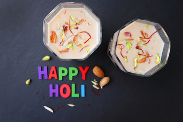 Indian Holi festival food or drink Thandai. It is an Indian cold drink prepared with a mixture of Milk, Dry fruits, sugar & spices. Garnished with Almonds, Pistachio & saffron. Happy Holi. copy space.