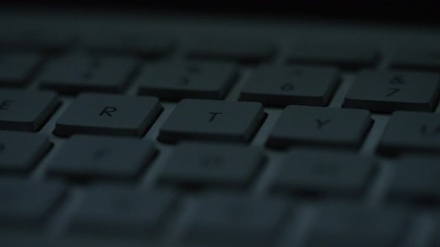 Camera pans across the keys of a keyboard in the dark