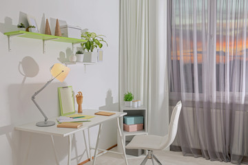 Stylish room interior with comfortable workplace near window. Design idea