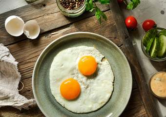 Tasty fried eggs for breakfast. Fried eggs in a plate on a wooden table background, top view.