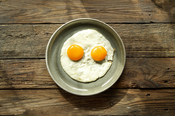 Scrambled eggs for breakfast. Perfect fried eggs in a gray plate. Isolated. Top view. Wood background.