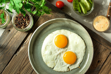 Tasty fried eggs for breakfast. Fried eggs in a plate on a wooden table background, top view.