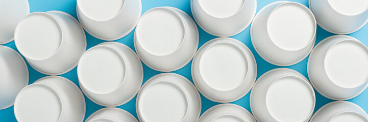 Inverted paper cups on a blue background. Banner. Flat lay, top view