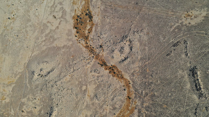 Fototapeta na wymiar Aerial top down view of Negev desert, Ezuz village. Sandy land surface from above. Beautiful patterns on earth. Texture, background. Israel.