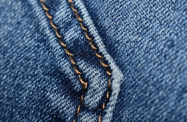 Machine stitching with brown thread on denim close up.