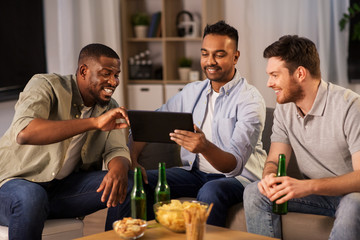 friendship, leisure and people concept - male friends with tablet pc computer drinking beer at home at night