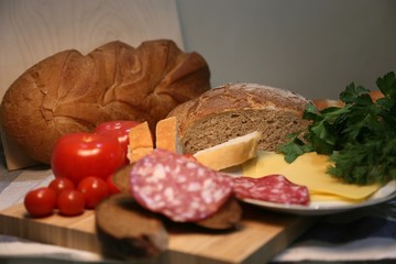 Delicious fresh bread and cheese pieces with sausage on a plate, side view