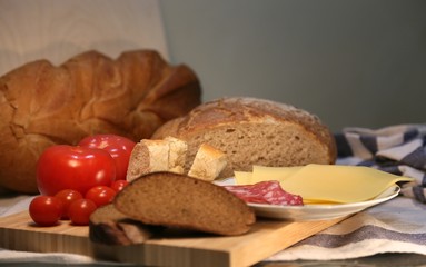 Delicious fresh bread and cheese pieces with sausage on a plate, side view