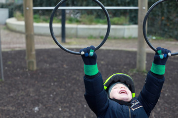 Child hanging on the gymnastic rings on the playground