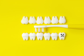 Toothbrush brushing teeth. Concept with yellow toothbrush, models of teeth with one sad tooth...