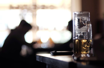 A drunk glass of light beer in a dark bar