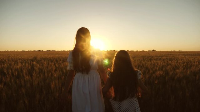 Free women travelers enjoy sunset over wheat field. Mom gently hugs daughter on background of a beautiful sunset. Adult daughter in arms of her mother in field in sun.