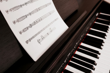 Music notebook with a piece of music and a violin key on a stand for an electric piano with white...