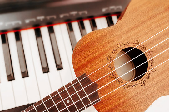 Musical instruments traditional ukulele ukulele on the background of an electric piano synthesizer. Learning to play musical instruments. Love of music.