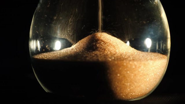 Round hourglass flask where grains of sand fall