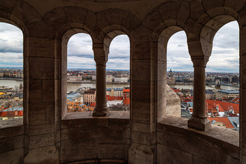 view of Budapest on Danube river through fisher bastion building under dramatic sky - from dark room