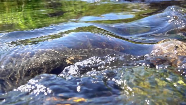 The waves on the surface of a clear stream; clear water in the sunlight