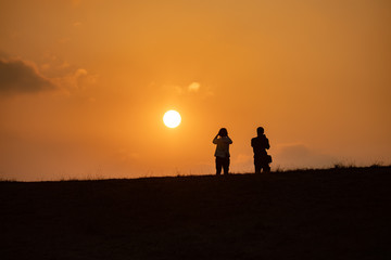 2 people standing and see sunset orange color