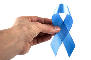 close up of male hand holding sky blue prostate cancer awareness ribbon over white background