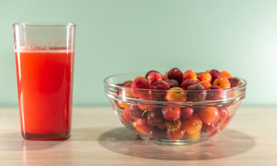 Fresh fruits and acerola juice on a wooden surface
