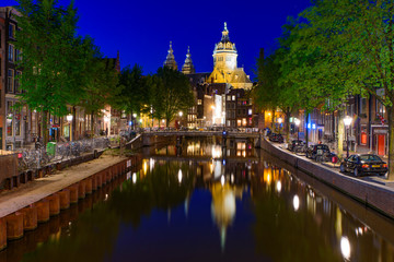 Fototapeta na wymiar Night view of buildings and boats along the canal in Amsterdam, Netherlands