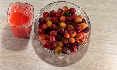 Fresh fruits and acerola juice on a wooden surface