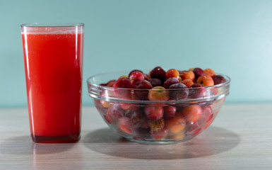 Fresh fruits and acerola juice on a wooden surface