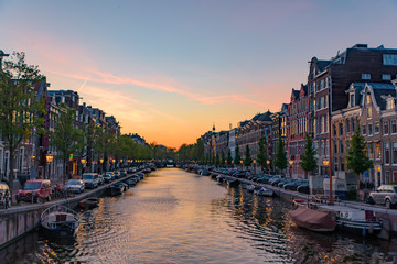 Fototapeta premium Buildings and boats along the canal at sunset time in Amsterdam, Netherlands
