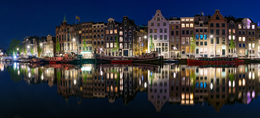 Fototapeta na wymiar Panorama of the buildings along the canal at night in Amsterdam, Netherlands