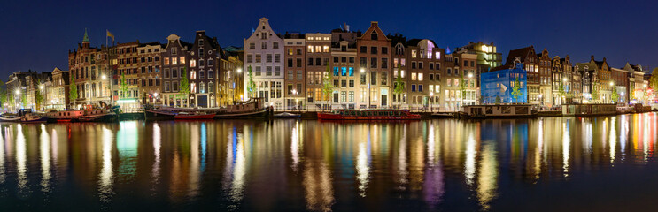 Fototapeta na wymiar Panorama of the buildings along the canal at night in Amsterdam, Netherlands