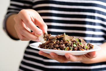 Traditional Northern Thai food, spicy minced pork salad (Larb Moo Kua) eating with sticky rice by hand