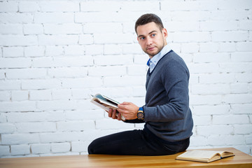 A young businessman guy sits at a table with a book