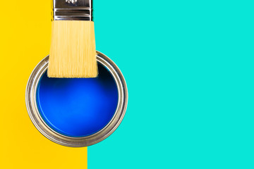hand holding Brush  on open can of  paint on pastel multicolor  background. Renovation concept -...