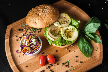 Vegetarian burger made of squash and tomato grilled courgette black background
