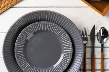 Glossy grey ceramic plate with cutlery on wooden kitchen table