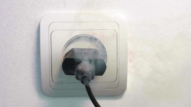 Slowmo smoke escapes from USB charger of phone connected to electrical outlet