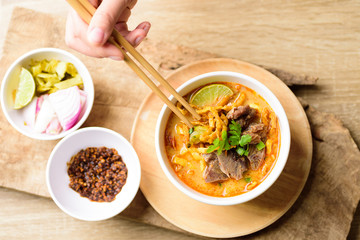 Traditional Northern Thai food (Khao Soi), spicy curry noodles soup with coconut milk and beef eating by chopsticks