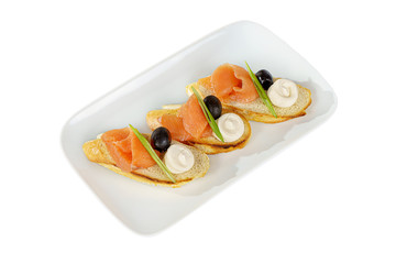 Cold appetizers sandwiches with fish salmon, green onions, olive, sauce on a square plate, white isolated background side view for the menu