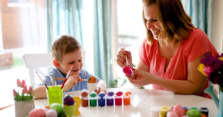 Obraz na płótnie Canvas Happy young mother and son are painting Easter eggs