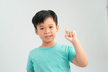 Smiling boy holding a capsule of vitamin on a white background