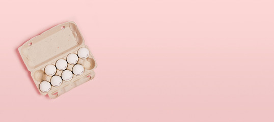 Happy Easter. White eggs with painted eyes in paper packaging on a pink background. Flat lay, top view, copy space.