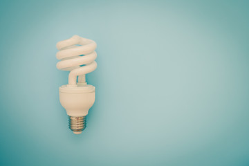 Glowing LED light bulb on blue background for energy savings concept