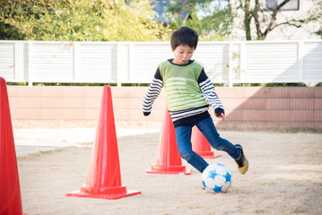 庭でサッカーの練習をする男の子